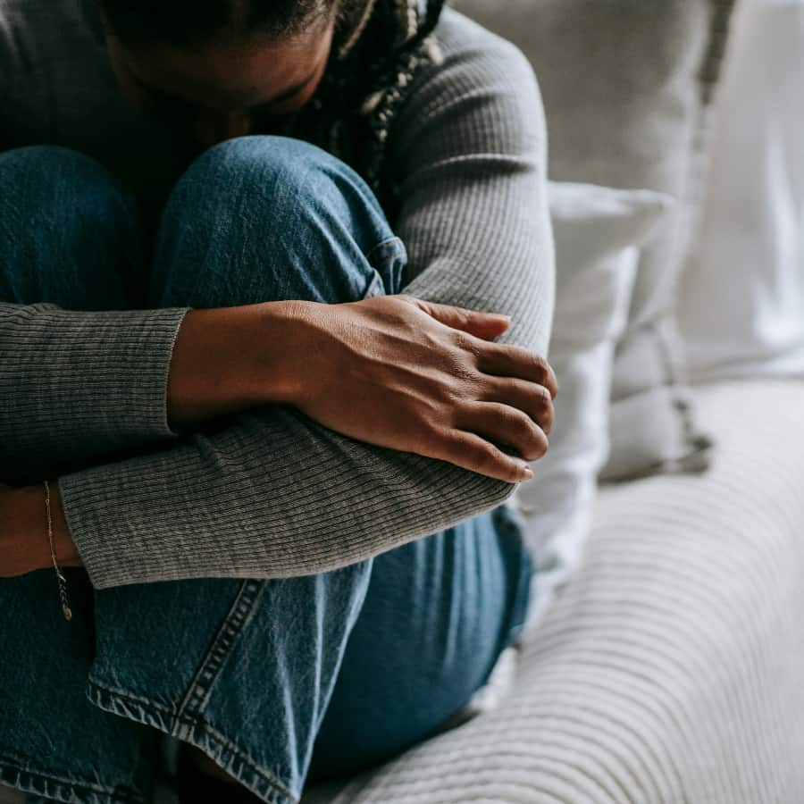 Woman holds her legs to her chest to show her need for grief treatment in Benton County