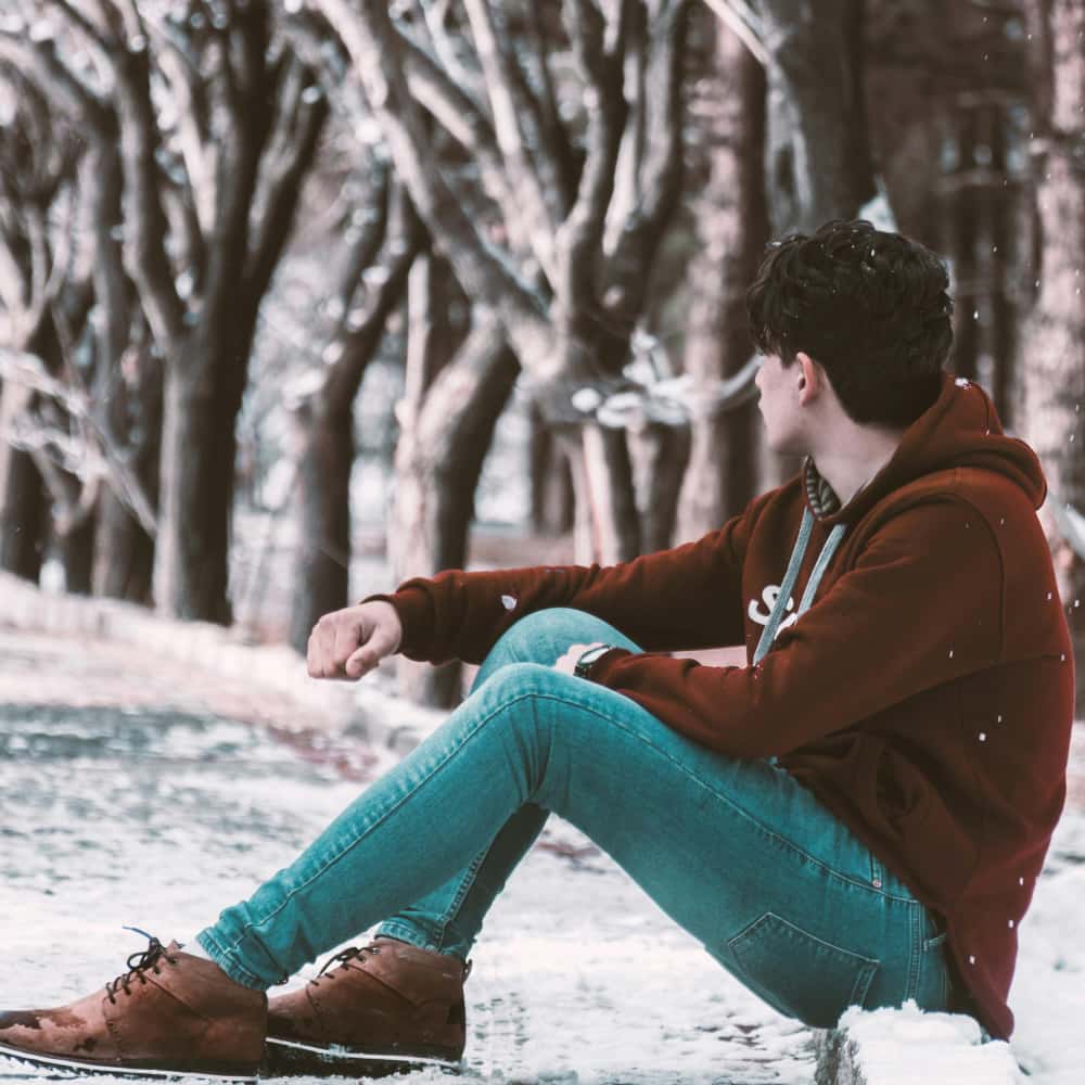 Man sits looking at a wooded path in the snow thinking about past trauma for current health as taught by Dr. Mate